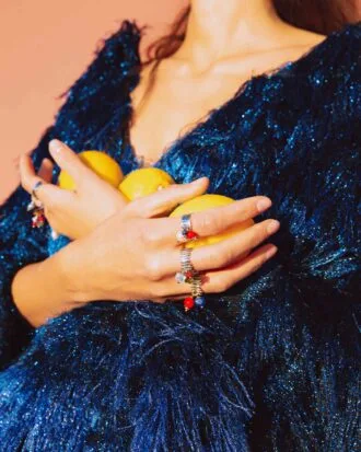 lady wearing rings colorful charms and holding lemons