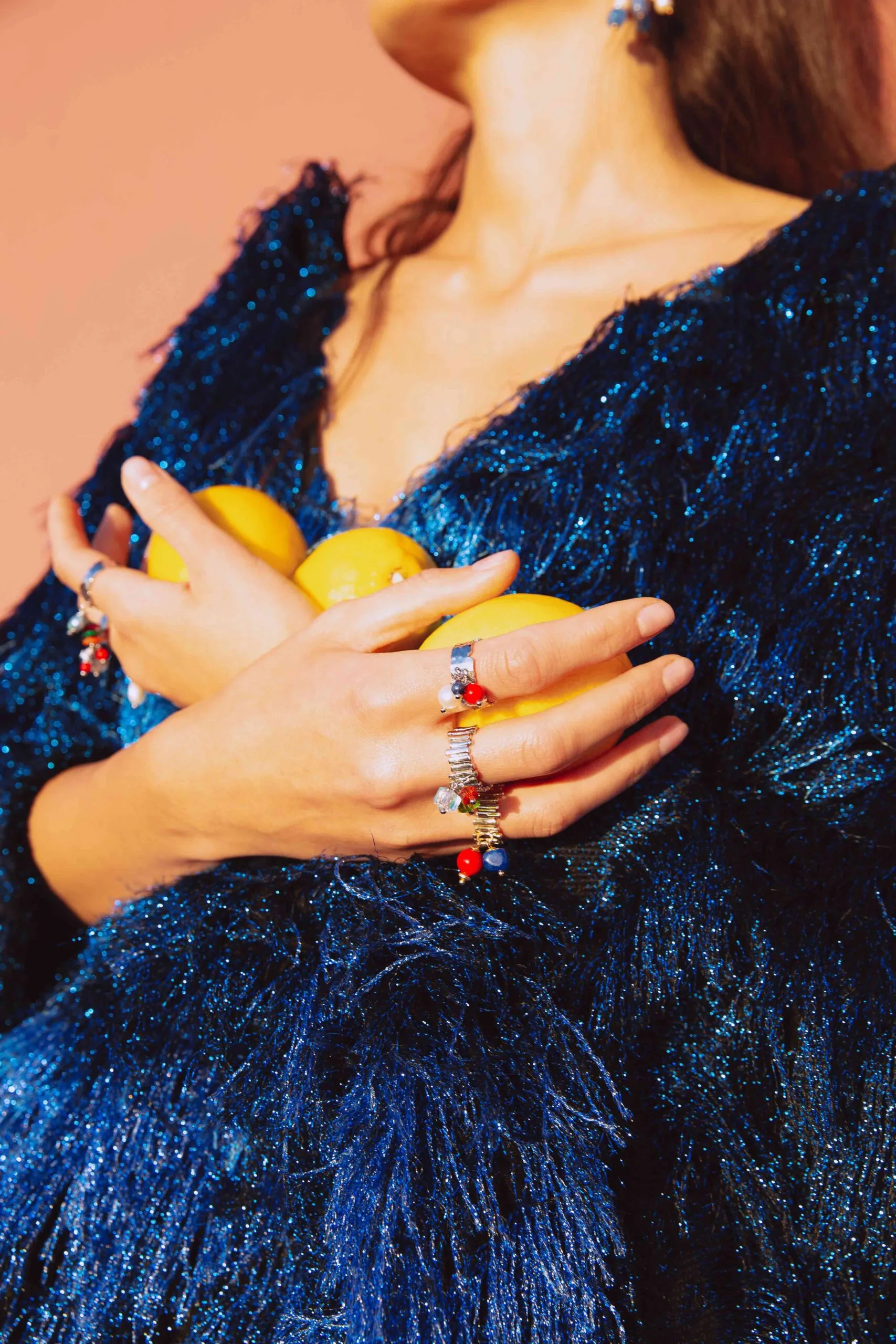 lady wearing rings colorful charms and holding lemons